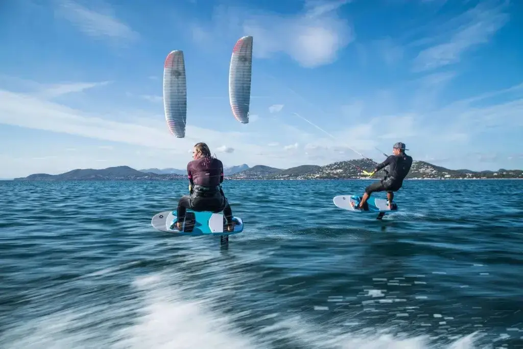 Due rider in foil sull'acqua con i kite in cielo, il confronto tra kitesurf e wing foil