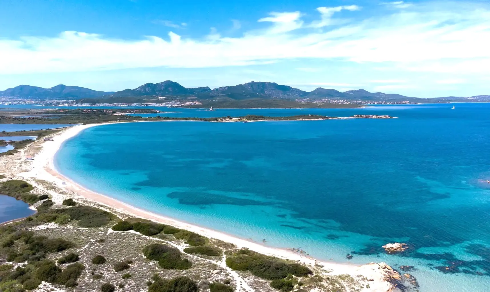 La baia delle Saline a Olbia con i kite colorati in acqua e la spiaggia sabbiosa