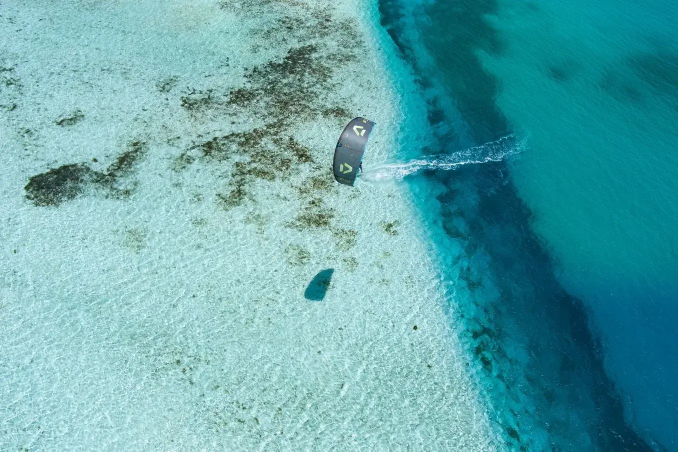 Vista aerea di un kiter che solca l'acqua turchese spinto dal vento alle Saline, Olbia